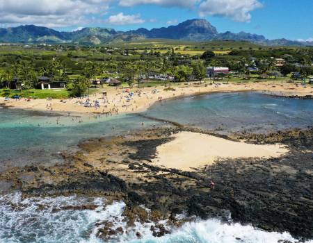 An aerial photo of Kauai coastline, with mountains in the distance