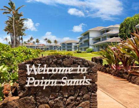 a stone sign with "Welcone to Poipu Sands" in white font
