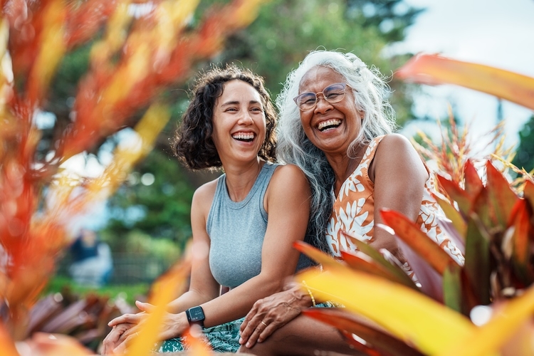 Two women smiling. a hawaiian mother and daughter smile and sit in a garden