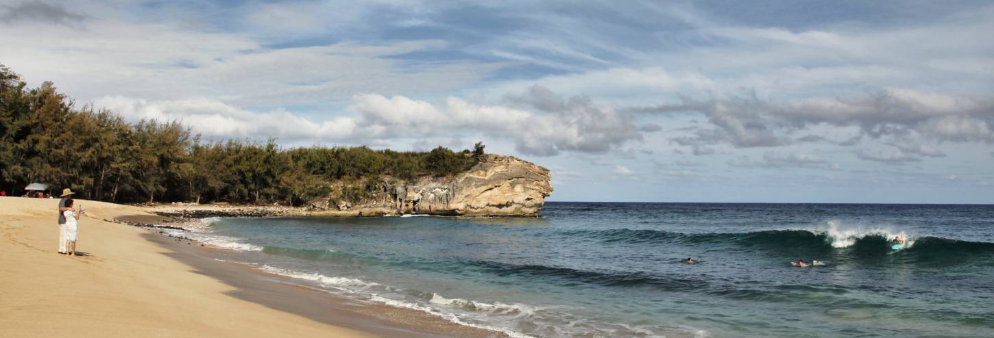 a wide shot of a couple taking photos on an empty shipwreck's beach