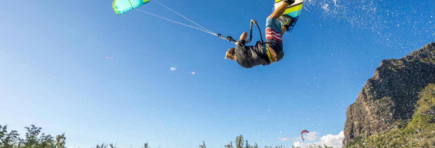 a windsurfer flips over the water in a cover near poipu
