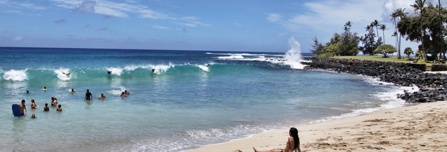 vacationers ride boards on shallow waves on a clear day at brennecke's beach