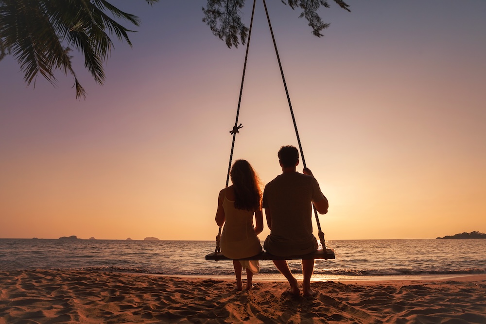 A silhouette of romantic couple on the beach during sunset.