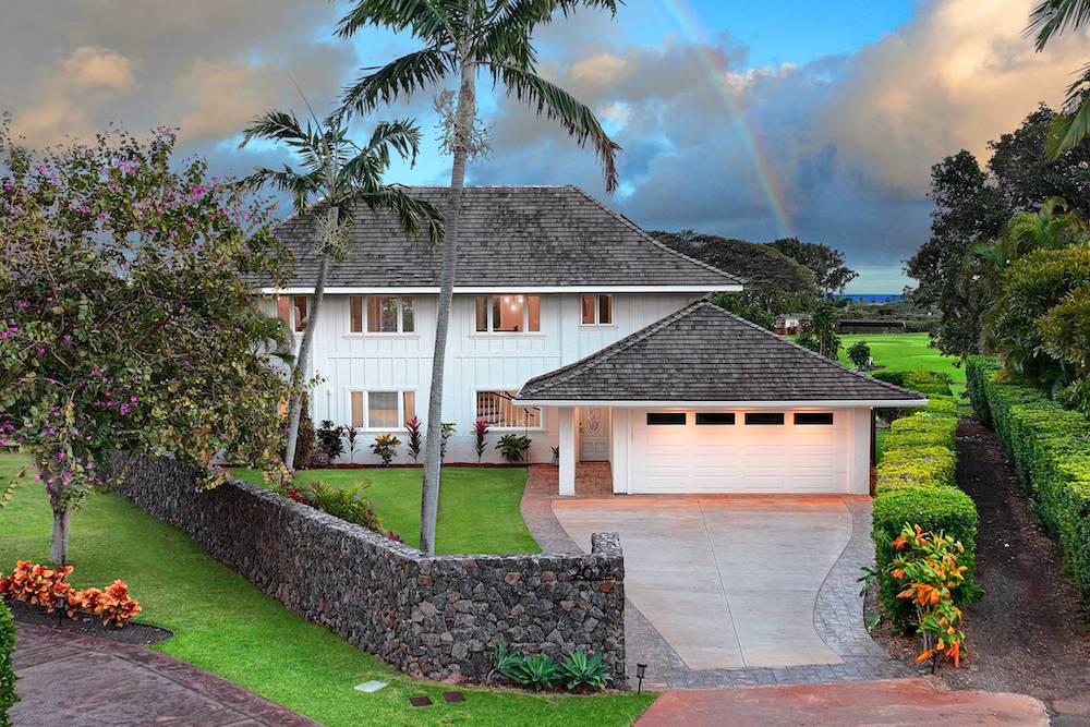 large white home in Kauai with rainbow in background